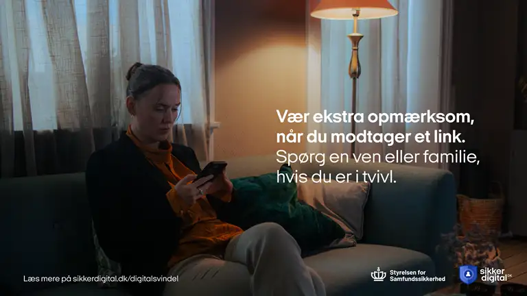 Kvinde sidder i sofa og kigger på sin mobil - Billede fra kampagnen om digital svindel 2025-2026